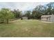 Expansive backyard featuring a large shed with covered parking, surrounded by mature trees and a wooden fence at 5490 Se Highway 42, Summerfield, FL 34491