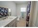 Well-lit bathroom features a modern vanity, toilet, shower with a floral curtain, and a window at 5490 Se Highway 42, Summerfield, FL 34491