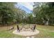 Outdoor fire pit with stone surround and seating in a wooded backyard offers a relaxing gathering space at 5490 Se Highway 42, Summerfield, FL 34491