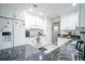 Well-lit kitchen with white cabinets, marble countertops, stainless appliances and a view to the living room at 5490 Se Highway 42, Summerfield, FL 34491