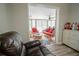 An open sunroom with ceiling fans and rattan seating is adjacent to the living room with a brown leather chair at 5490 Se Highway 42, Summerfield, FL 34491