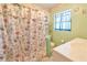 Traditional bathroom with a floral shower curtain, green walls, and a window providing natural light at 5812 Luzon Pl, Orlando, FL 32839