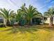 A well-maintained backyard showing healthy green grass, tropical trees, and a screened-in patio area at 805 Pickett Rd, The Villages, FL 32163