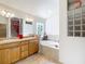 Bright bathroom with dual sinks, a soaking tub, and unique glass block accents at 805 Pickett Rd, The Villages, FL 32163