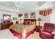 Elegant bedroom featuring tray ceilings, a plush bed, and a cozy reading chair at 805 Pickett Rd, The Villages, FL 32163