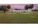 The front of the house is complemented by palm trees and a sprawling lawn during dusk at 8947 Se 70Th Ter, Ocala, FL 34472