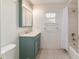 Well-lit bathroom featuring a blue vanity, tiled floors, and shower-tub combination at 905 Se 12Th St, Ocala, FL 34471