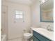 Bright bathroom featuring a white toilet, blue vanity, and tiled shower at 905 Se 12Th St, Ocala, FL 34471