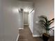 Neutral-toned hallway with wood-look flooring, a storage closet, and a decorative palm plant at 9681 Sw 97Th Ln, Ocala, FL 34481