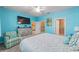 Bright main bedroom featuring blue walls, ceiling fan, TV, and ensuite bathroom and walk in closet at 9839 Sw 99Th Loop, Ocala, FL 34481