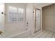 Well-lit bathroom featuring a bathtub, glass block window, and a glass shower enclosure at 11569 Sw 71St Cir, Ocala, FL 34476