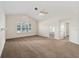 Bright living room with vaulted ceiling, fan, neutral carpet, and abundant natural light from the large window at 11569 Sw 71St Cir, Ocala, FL 34476