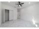 A bright bedroom features a closet, white walls, modern fan, and sleek marble floors that enhance the room's appeal at 12882 Se 42Nd Ct, Belleview, FL 34420