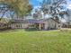 Welcoming single-story home with stone accents, a well-manicured lawn, and mature trees offering shade at 16211 Se 62Nd Pl, Ocklawaha, FL 32179