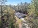 An aerial view showcases a single-story home with a long driveway surrounded by tall trees at 18301 Sw 69Th Loop, Dunnellon, FL 34432