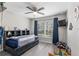 Bright bedroom with a ceiling fan, a window with blue curtains, and gray wood-look floors at 18301 Sw 69Th Loop, Dunnellon, FL 34432