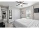 Bedroom with a ceiling fan, a window with white curtains, gray wood-look floors, and ensuite bathroom at 18301 Sw 69Th Loop, Dunnellon, FL 34432