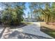 Long driveway leading to a modern home with an attached garage, surrounded by lush greenery at 18301 Sw 69Th Loop, Dunnellon, FL 34432