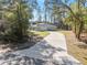 A charming home with a long driveway, set against a backdrop of lush trees and blue skies at 18301 Sw 69Th Loop, Dunnellon, FL 34432