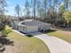 Exterior view of single-story home, features garage, lush lawn and long, curving driveway at 18301 Sw 69Th Loop, Dunnellon, FL 34432