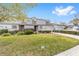 Charming townhouse exterior featuring well-manicured lawn, shrubs, dormer windows, and attached garages at 1947 Se 37Th Court Cir, Ocala, FL 34471