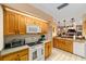 Well-lit kitchen featuring wood cabinets, white appliances, and a view into an adjacent living space at 1947 Se 37Th Court Cir, Ocala, FL 34471