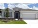 Charming single-story home with a manicured lawn, gray stucco, stone accents, and attached two car garage at 3071 Canopy Oak Blvd, Wildwood, FL 34785