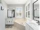 Bright main bathroom featuring double sinks, a soaking tub under a window, and tiled floors at 4731 Se 32Nd St, Ocala, FL 34480