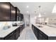 This modern kitchen features dark cabinetry, stainless appliances, granite countertops, and an island with barstool seating at 5370 Sw 45Th Ave, Ocala, FL 34474