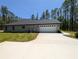 Rear exterior view of house, showcasing attached garage and ample parking at 8303 Sw 127 Ave, Dunnellon, FL 34432