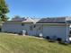 Rear exterior of home, solar panels on roof, manicured lawn, and various utilities at 8504 Sw 84Th Loop, Ocala, FL 34481