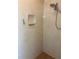 Walk-in shower featuring travertine walls, a built-in shelf, and dual shower heads at 8504 Sw 84Th Loop, Ocala, FL 34481