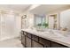 Bright bathroom featuring double sinks, dark cabinetry, and a walk-in shower with a glass door at 8667 Sw 44Th Ter, Ocala, FL 34476