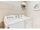 Clean laundry room with a white washer and dryer, and an open wire shelf for storage at 8667 Sw 44Th Ter, Ocala, FL 34476