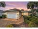 Charming single-story home with a well-manicured lawn, brick driveway, and a two-car garage at dusk at 8669 Sw 88Th Loop, Ocala, FL 34481