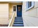 Charming blue front door with glass panes and gray steps leading up to a yellow house at 903 Ne 2Nd St, Ocala, FL 34470