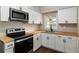 Kitchen features a stainless steel microwave, stove, wooden countertop, and white cabinets at 903 Ne 2Nd St, Ocala, FL 34470