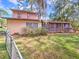 Exterior side-view of the home featuring a partially fenced yard and mature trees at 1022 Ne 11Th Ave, Ocala, FL 34470