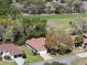 Aerial view of a charming home with red roof surrounded by lush greenery and a golf course at 11587 Sw 72Nd Cir, Ocala, FL 34476