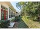 Exterior view showcasing the sunroom with lush landscaping, red doors, and a serene outdoor space at 11587 Sw 72Nd Cir, Ocala, FL 34476