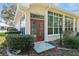 Charming exterior view featuring a bright sunroom with large windows, red doors, and garden space at 11587 Sw 72Nd Cir, Ocala, FL 34476