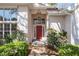 Inviting entryway with a red door, sidelights, transom window, and flowering bushes at 11587 Sw 72Nd Cir, Ocala, FL 34476