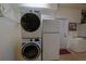 Laundry room with stacked washer/dryer, laundry sink, and a white refrigerator at 13128 Se 97Th Terrace Rd, Summerfield, FL 34491