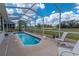 Refreshing screened-in pool with lounge chairs and a backdrop of a lush golf course at 13128 Se 97Th Terrace Rd, Summerfield, FL 34491