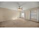 A spacious bedroom featuring plush carpet, a ceiling fan, and natural light from two windows at 14059 Sw 47Th Ave, Ocala, FL 34473