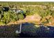 Aerial view of a peaceful lake featuring a wooden dock and lush trees bordering the shoreline of the expansive lot at 14540 Ne 250Th Ave, Fort Mc Coy, FL 32134