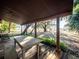 Covered porch showcasing an outdoor dining table, benches, and peaceful water views at 14540 Ne 250Th Ave, Fort Mc Coy, FL 32134