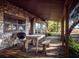 Covered porch featuring a stone exterior, dining table, grill, and outdoor seating for relaxation and entertainment at 14540 Ne 250Th Ave, Fort Mc Coy, FL 32134
