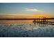 Scenic lake view featuring a wooden dock at sunset, reflecting light, and still waters at 14540 Ne 250Th Ave, Fort Mc Coy, FL 32134