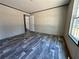 Empty bedroom featuring modern gray wood flooring, neutral walls, and a sunlit window at 1921 Nw 120Th Ave, Ocala, FL 34482